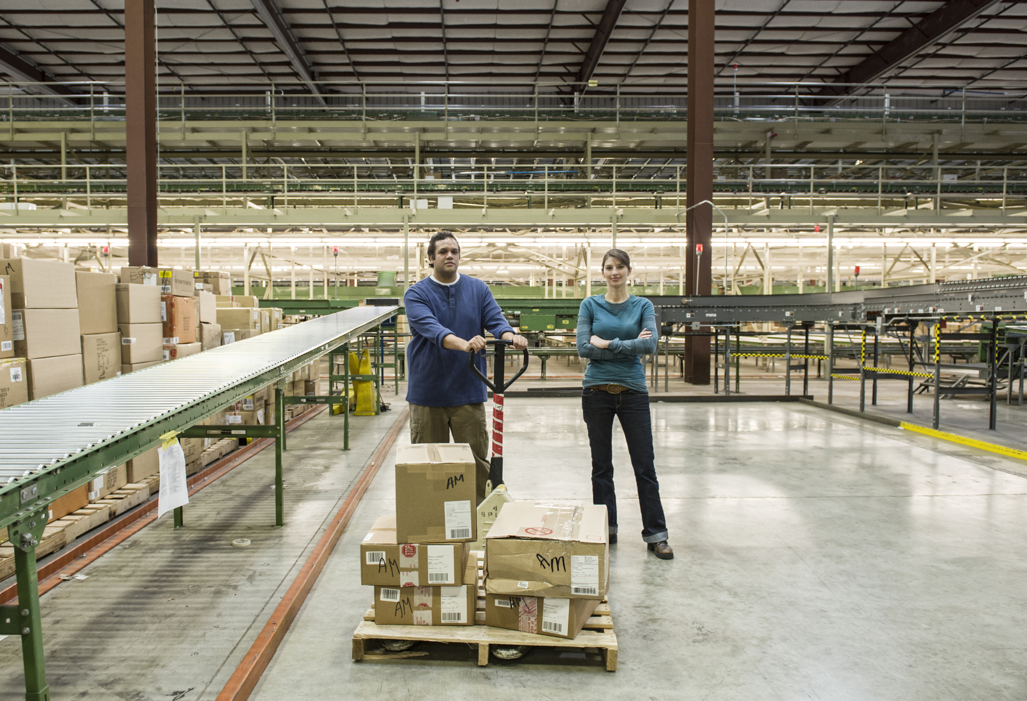 Caucasian male and female workers in a large distribution warehouse.